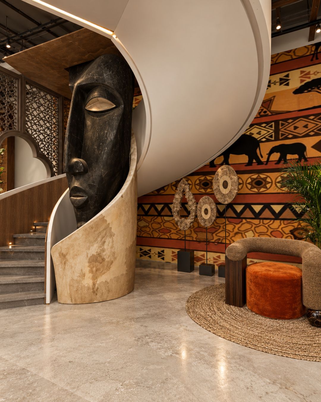 Spiral staircase with a sculpted mask feature beside an African-pattern mural, designed by Lispace